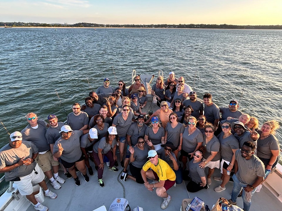 The Best Spring Fishing on Long Island 3 Corporate group in matching shirts posing on Celtic Quest upper deck at sunset